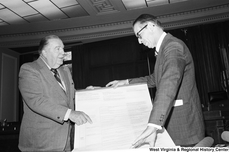 Jennings Randolph and another man examine a large print of a Washington family tree.