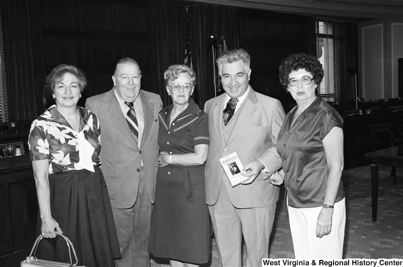 Jennings Randolph stands with a group of women and men, one of whom holds a book entitled "Washington: The Indispensable Man".