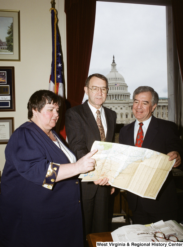 Photograph of Congressman Nick Rahall and two unidentified people looking over a map