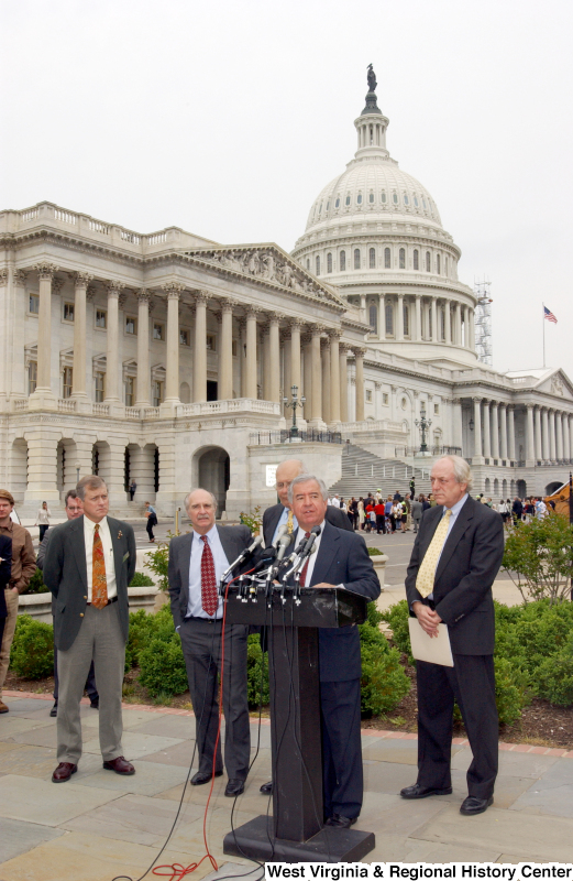 Congressman Rahall, John Dingell, Jr., and other men stand at a podium during a press conference in front of the Capitol Building.