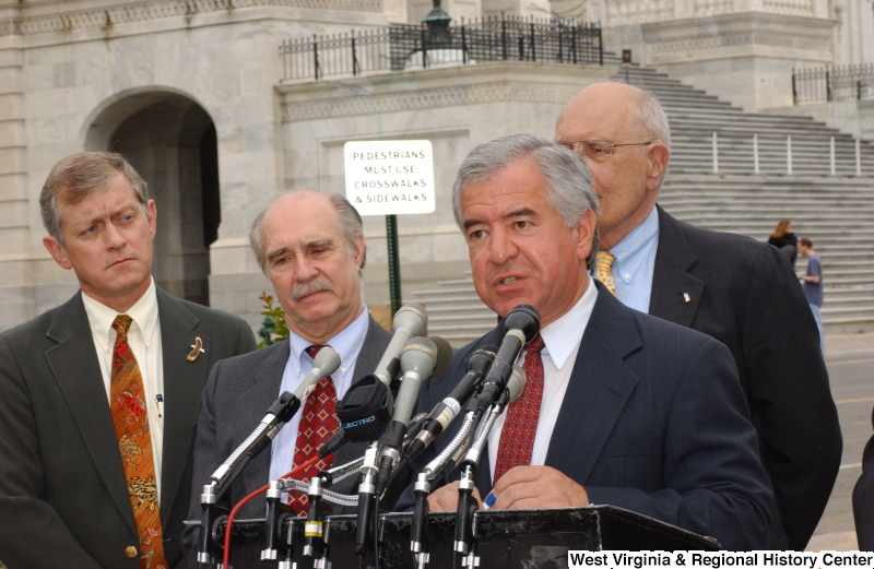 Congressman Rahall, John D. Dingell, and two other men stand at a podium during a press conference in front of the Capitol Building.