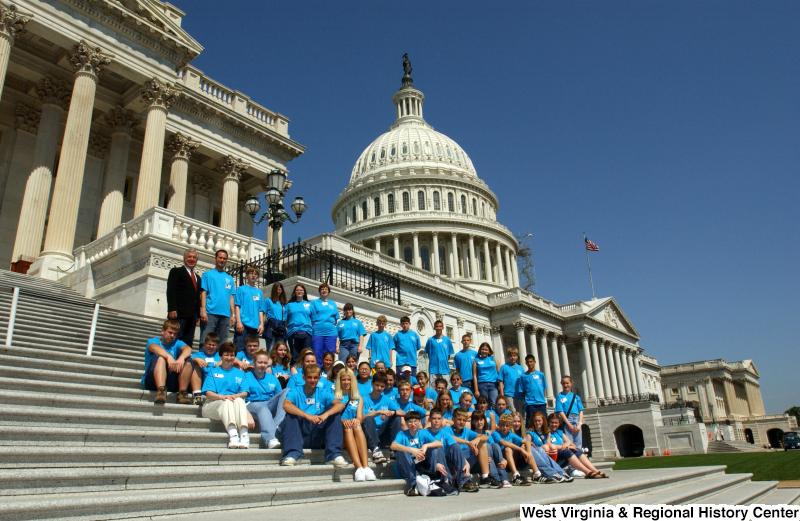 Congressman Rahall stands with children in blue shirts on the steps of the Capitol Building.