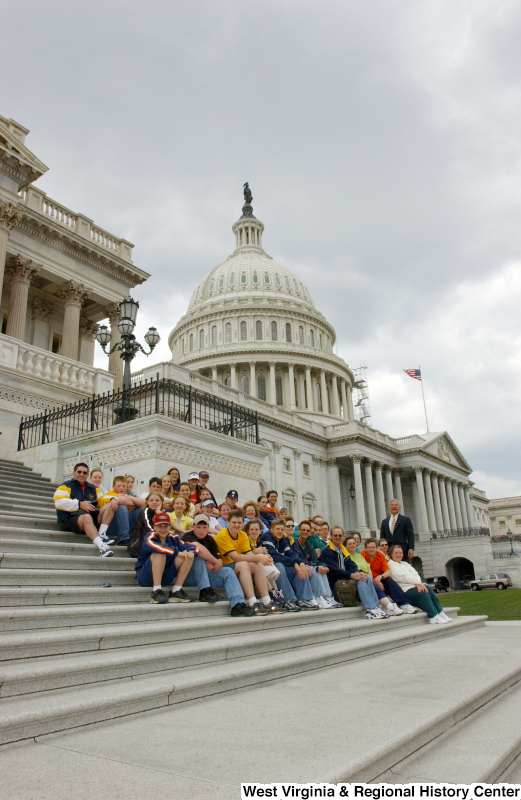 Congressman Rahall stands while people sit on the steps of the Capitol Building.