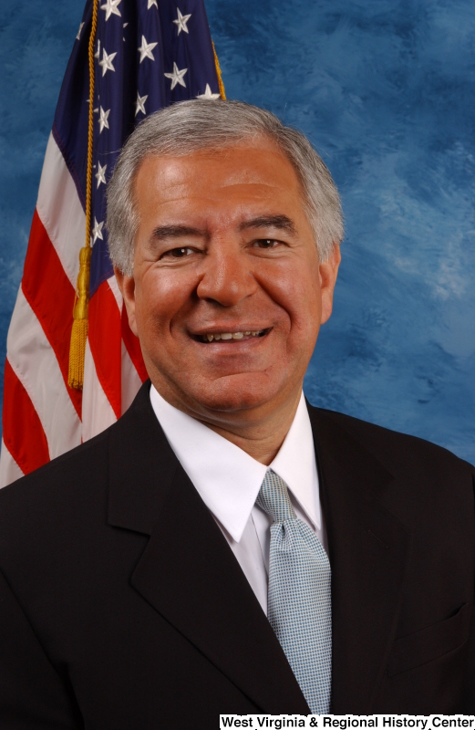 Congressman Rahall poses in front of the U.S. flag and a blue background  (portrait).