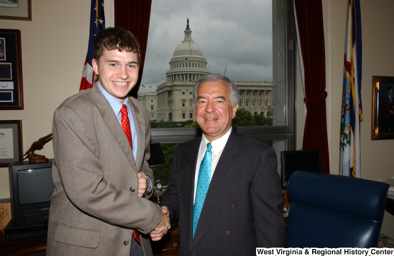 Congressman Rahall stands with a man wearing a taupe suit and red tie in his Washington office.