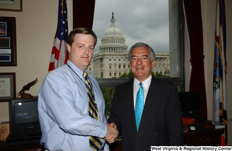 Congressman Rahall stands in his Washington office with a man wearing a blue shirt and striped tie.