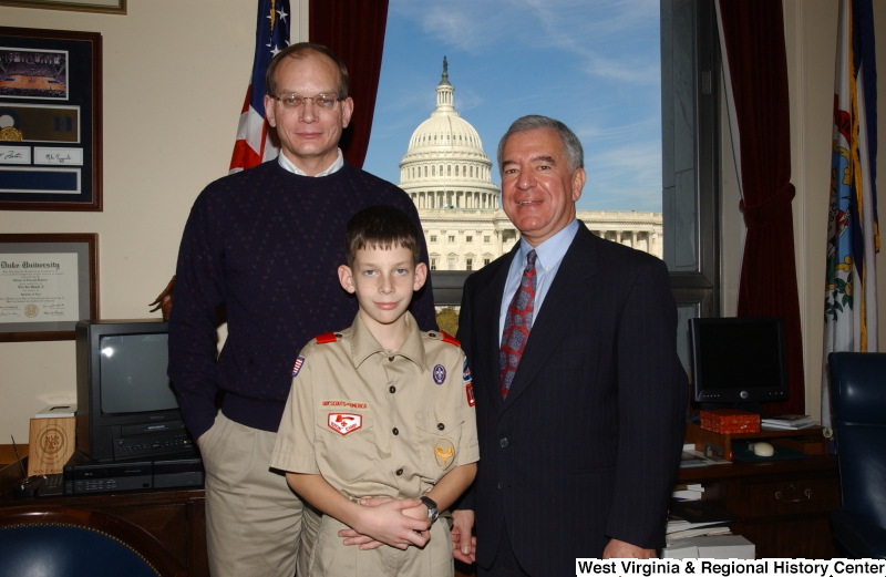 Congressman Rahall stands in his Washington office with a man and a Boy Scout.