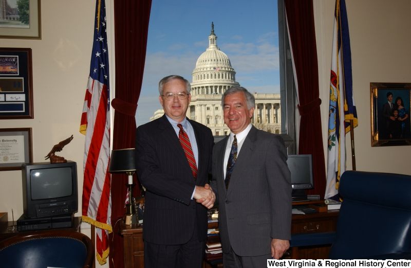 Congressman Rahall stands in his Washington office with a man wearing a pinstripe suit and red striped tie.