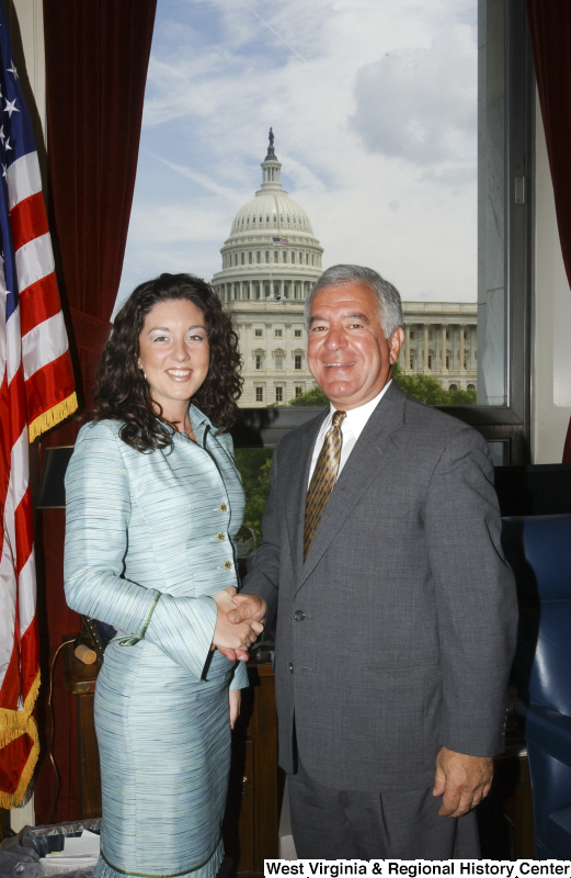 Congressman Rahall stands in his Washington office with a woman wearing an aqua dress.