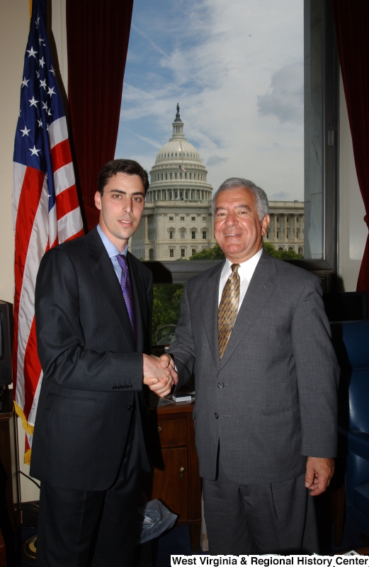 Congressman Rahall stands in his Washington office with a man wearing a black suit and purple tie.