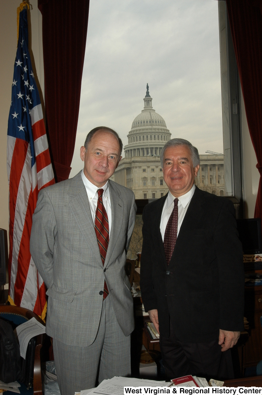 Congressman Rahall stands in his Washington office with a man wearing a grey suit and red and blue striped tie.