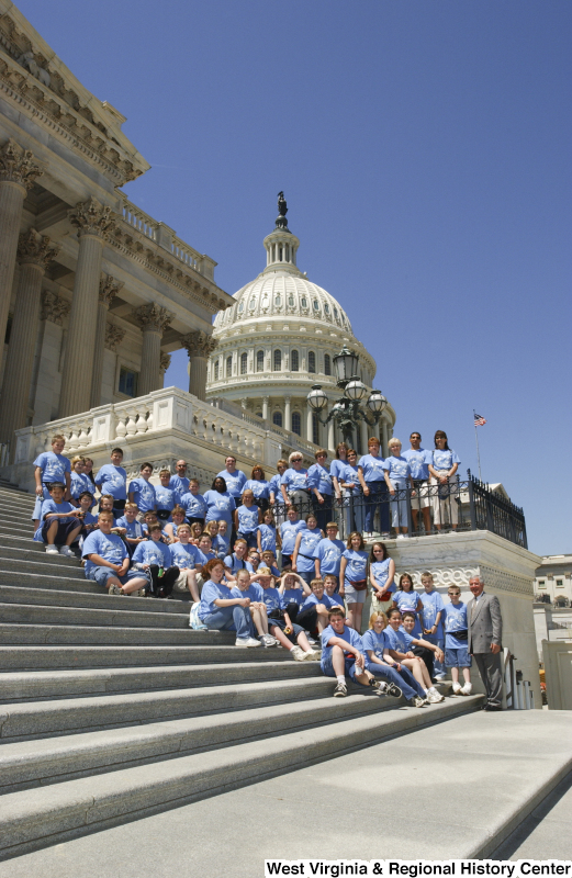 Congressman Rahall stands on the steps of the Capitol Building with children and adults wearing blue shirts containing an image of West Virginia.