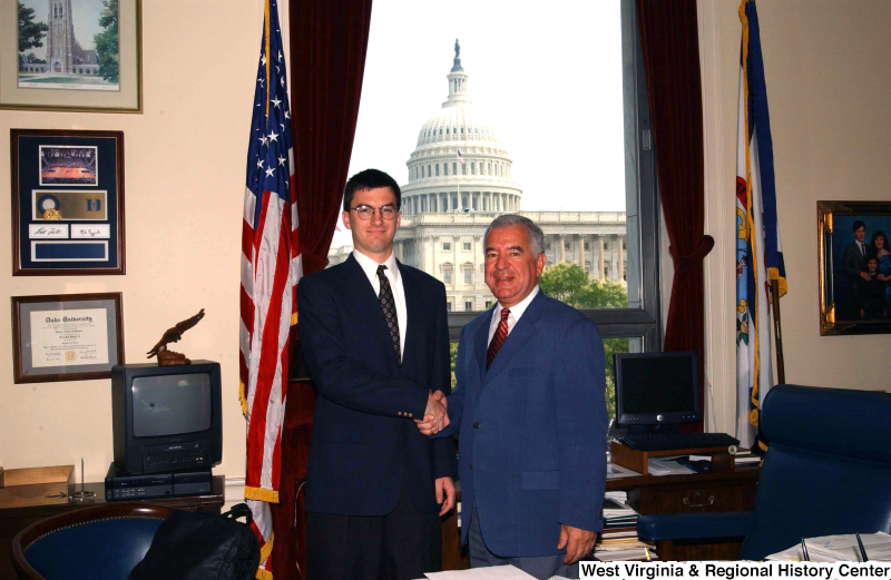 Congressman Rahall in his Washington office shakes hands with a man in a dark blue suit.