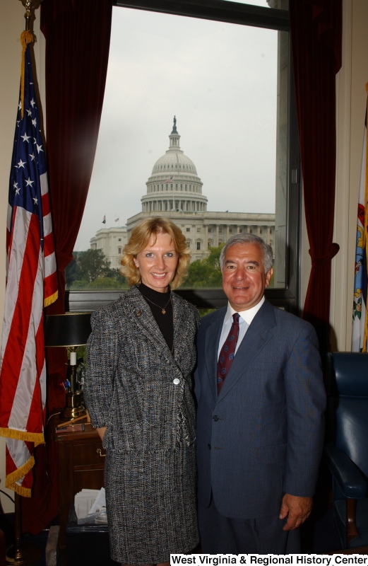 Congressman Rahall stands in his Washington office with a woman wearing a frilled jacket with skirt.