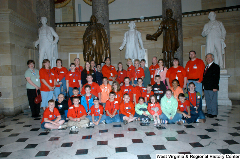 Congressman Rahall stands with a group of children and adults, most of whom are wearing orange shirts, and statues.