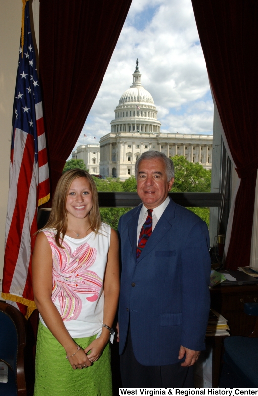 Congressman Rahall stands in his Washington office with a woman wearing a floral-print shirt and green skirt.