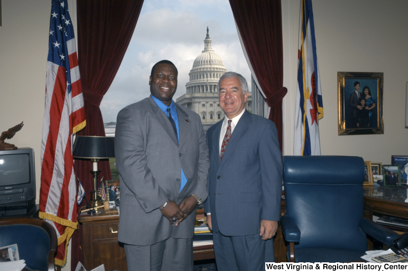 Congressman Rahall in his Washington office stands with a man wearing a grey suit and bright blue shirt.