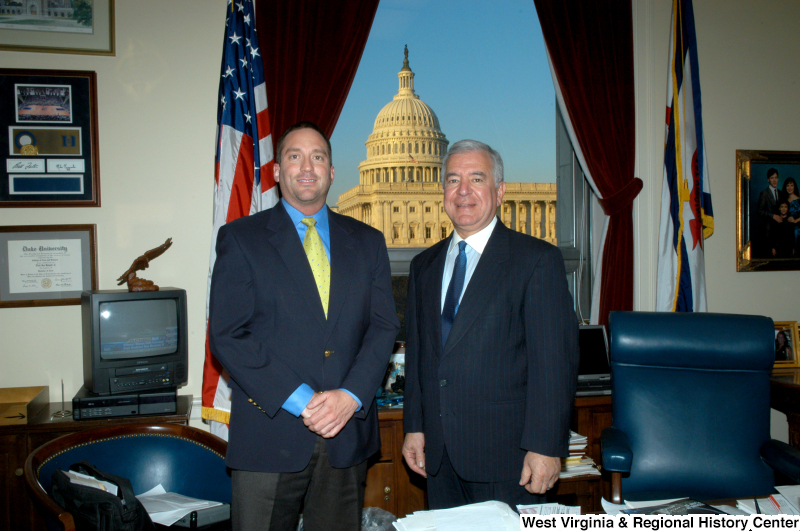 Congressman Rahall stands in his Washington office with a man wearing a blue blazer, blue shirt, and yellow tie.