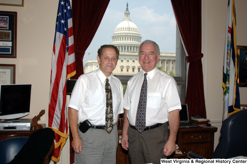 Congressman Rahall stands in his Washington office with another man wearing white short-sleeve shirts.