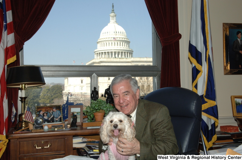 Congressman Rahall sits in his Washington office with a dog wearing a pink sweater and ribbons.