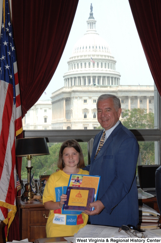 Congressman Rahall stands in his Washington office with a girl holding materials labeled 2007 Children's Congress and wearing a shirt with the logo for Juvenile Diabetes Research Foundation International.