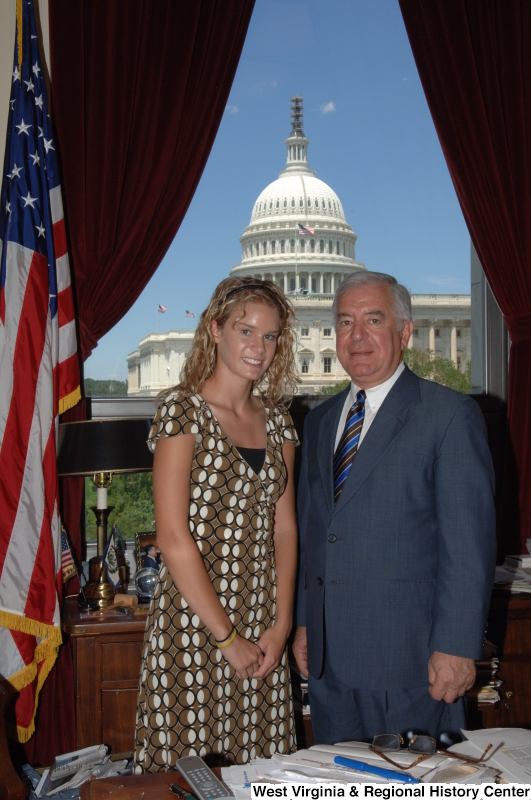 Congressman Rahall stands in his Washington office with a woman wearing a brown, white, and black dress.