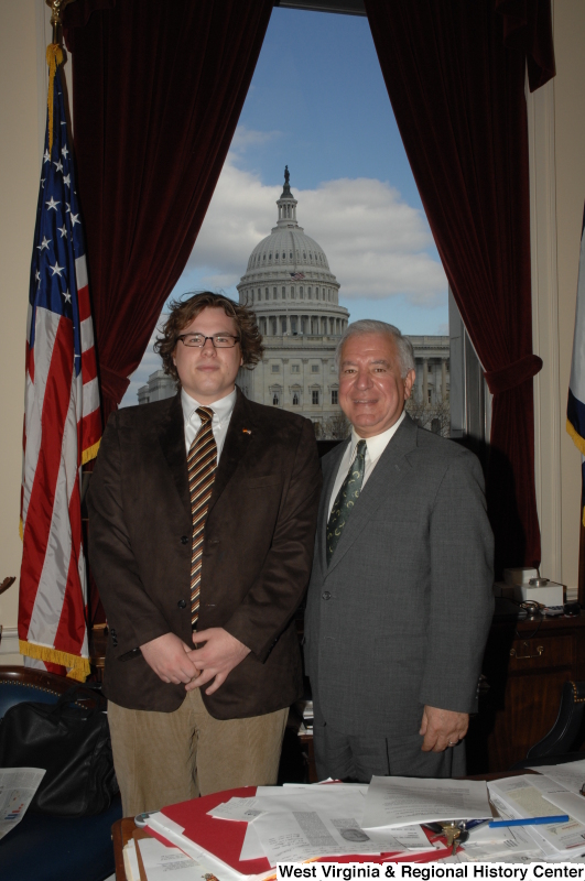 Congressman Rahall stands in his Washington office with a man wearing a brown jacket and striped tie.