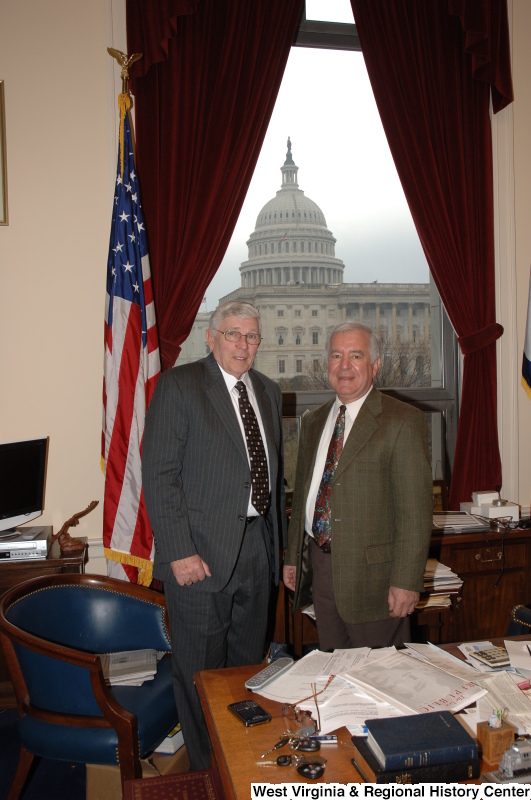 Congressman Rahall stands in his Washington office with a man wearing a grey pinstripe suit and square-patterned tie.