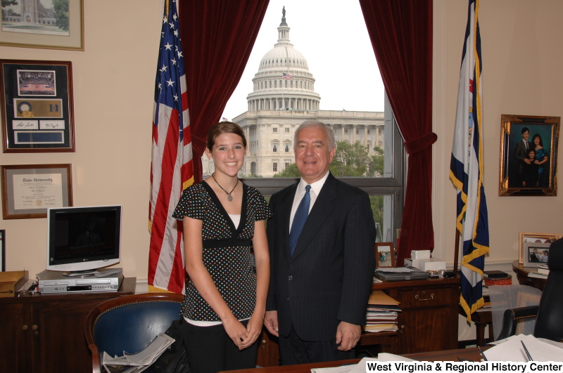 Congressman Rahall stands in his Washington office with a young woman wearing a spotted blouse.