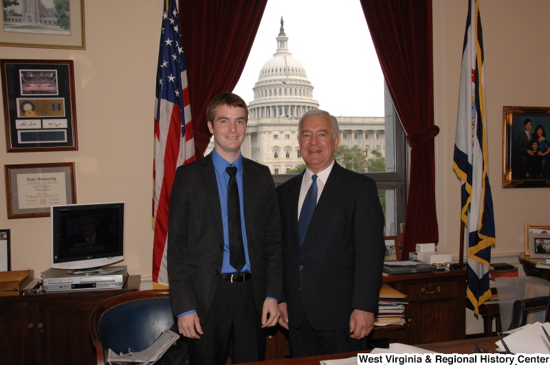 Congressman Rahall stands in his Washington office with a man wearing a black suit, blue shirt, and black tie.