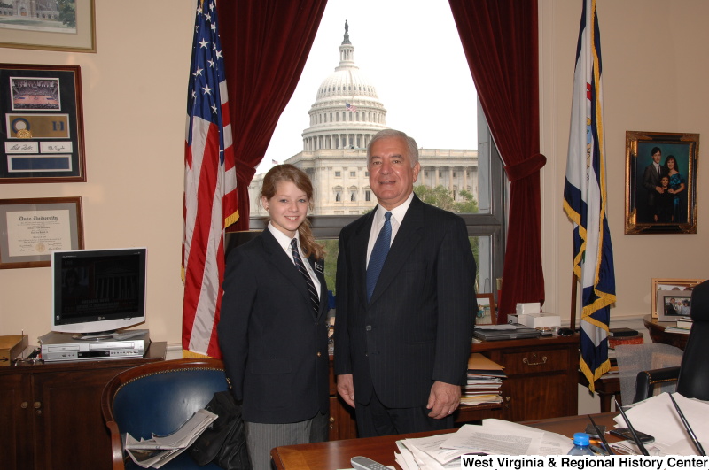 Congressman Rahall stands in his Washington office with a young woman wearing a black blazer and striped tie.
