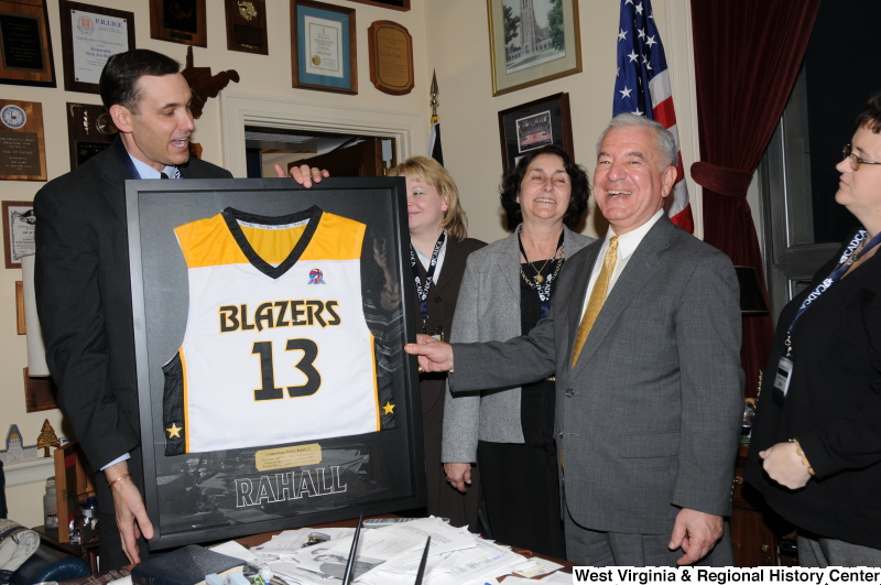 Congressman Rahall stands with a framed West Virginia Blazers jersey and four other people in his Washington office.