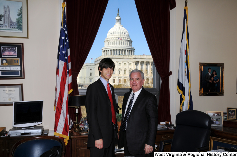 Congressman Rahall stands in his Washington office with a young man wearing a dark suit and red tie.