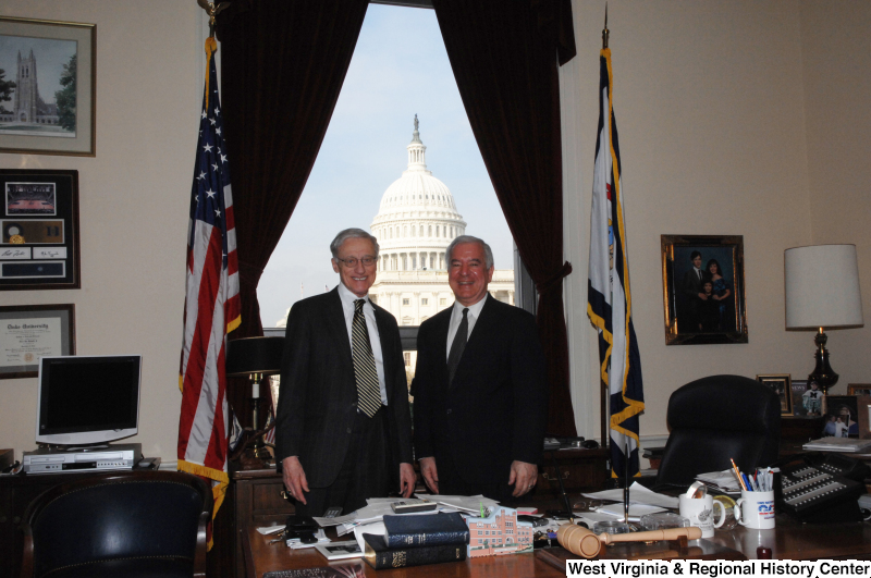 Congressman Rahall stands in his Washington office with a man wearing a dark pinstripe suit and black and yellow striped tie.