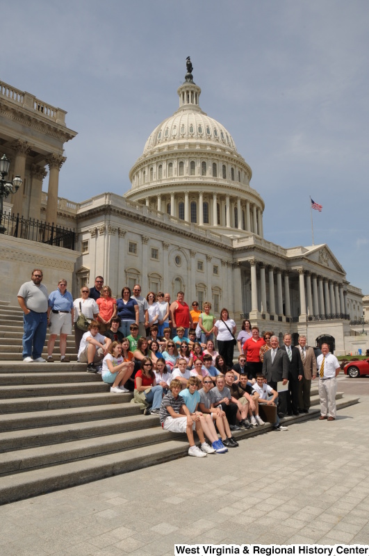 Congressman Rahall stands with a group of adults and children on the steps of the Capitol Building.