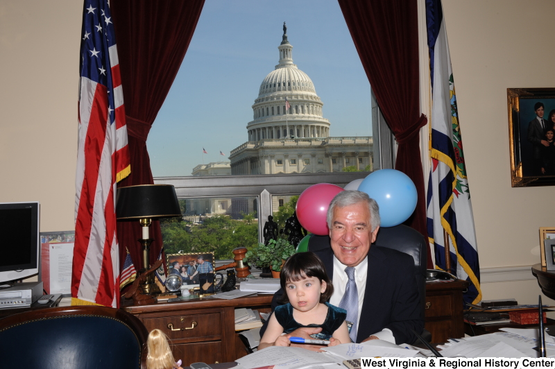 Congressman Rahall sits in his Washington office with a girl and balloons.