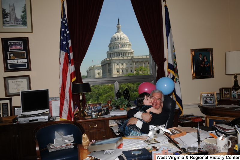 Congressman Rahall hugs a girl in his Washington office, with balloons.