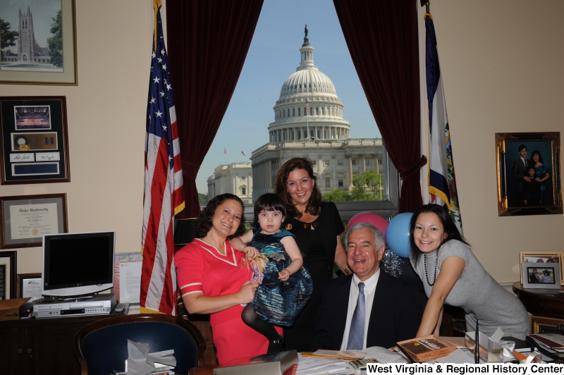 Congressman Rahall sits in his Washington office with three women and a girl, with balloons.