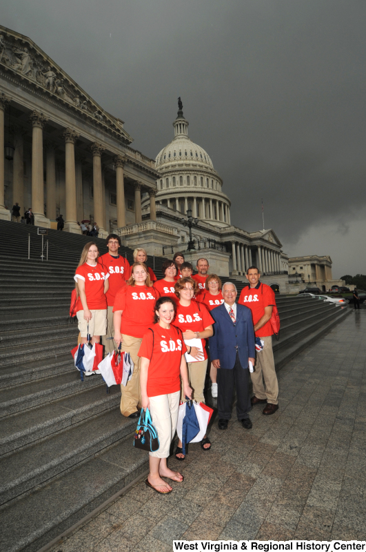 Congressman Rahall stands on the steps of the Capitol Building with a group of people wearing red "S.O.S." shirts.