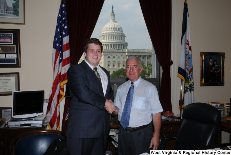 Congressman Rahall in his Washington office shakes hands with a man wearing a dark blue suit.
