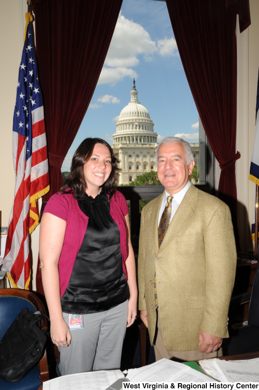 Congressman Rahall stands in his Washington office with a woman wearing a black shirt and magenta sweater.