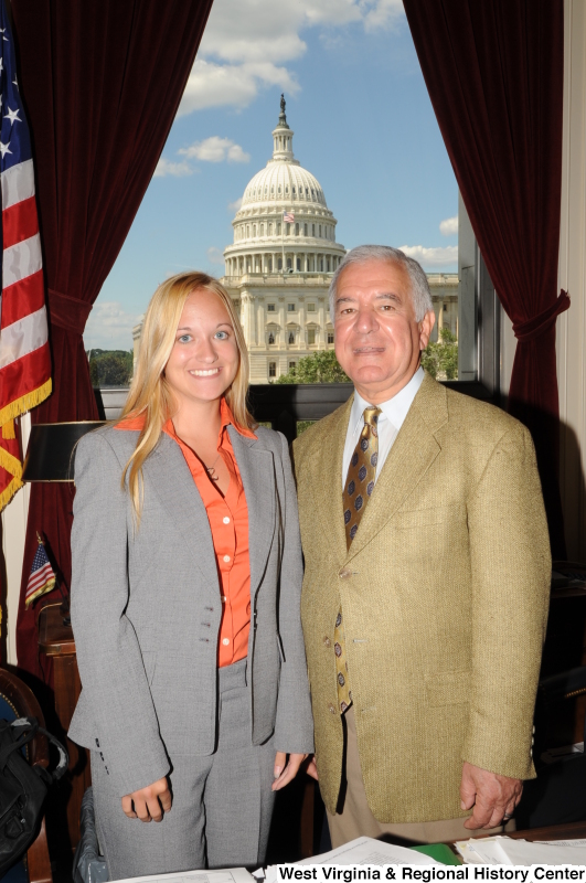 Congressman Rahall stands in his Washington office with a woman wearing a grey suit and orange shirt.