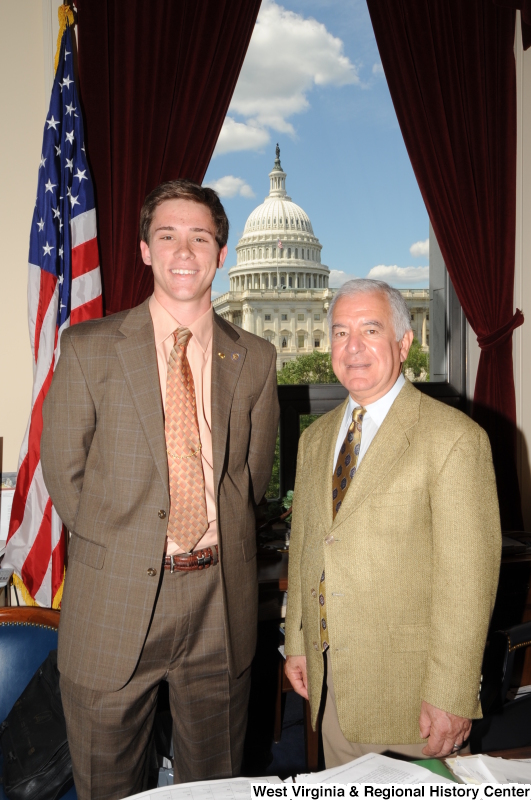 Congressman Rahall stands in his Washington office with a man wearing a brown windowpane suit.