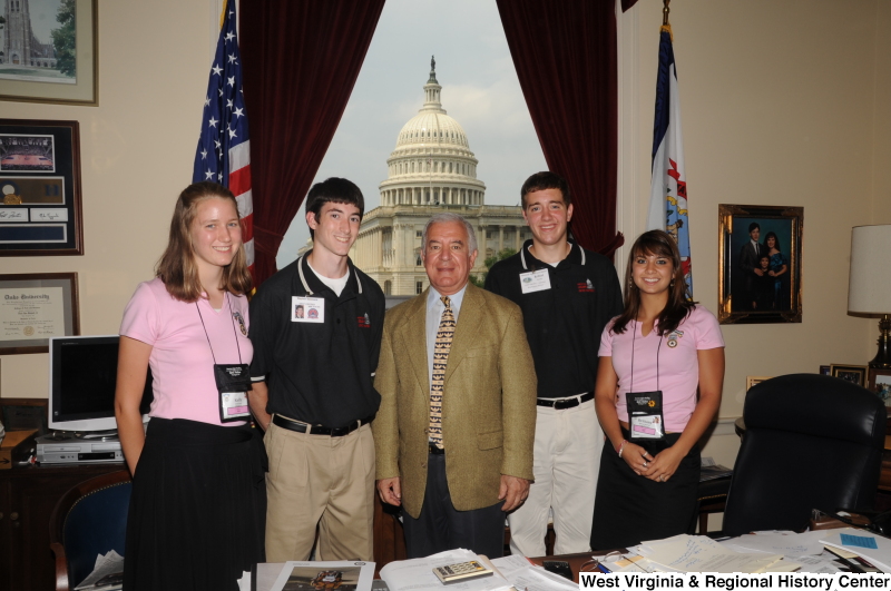 Congressman Rahall stands in his Washington office with two young men and two young women wearing name badges.