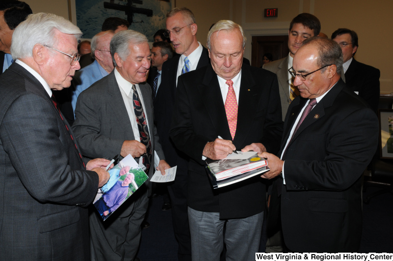 Congressman Rahall and others look on while a man signs autographs.