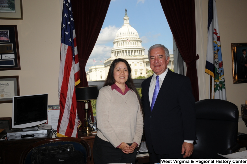 Congressman Rahall stands in his Washington office with a woman wearing a beige sweater and magenta shirt.