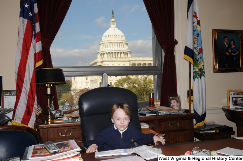 A boy sits in Congressman Rahall's chair in his Washington office.