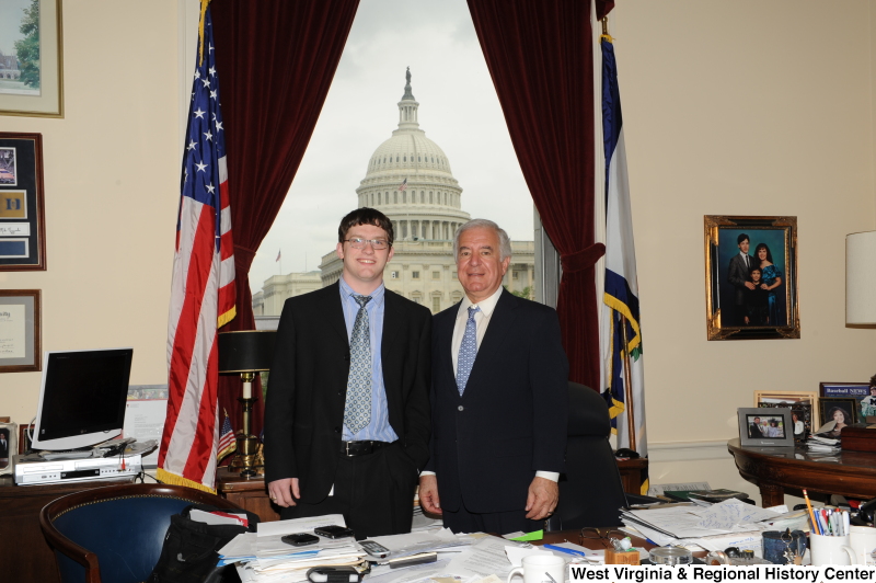 Congressman Rahall stands in his Washington office with a young man wearing a dark suit and blue and silver tie.