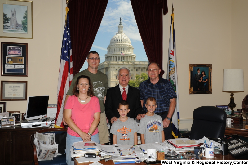 Congressman Rahall stands in his Washington office with two men, a woman, and two boys.