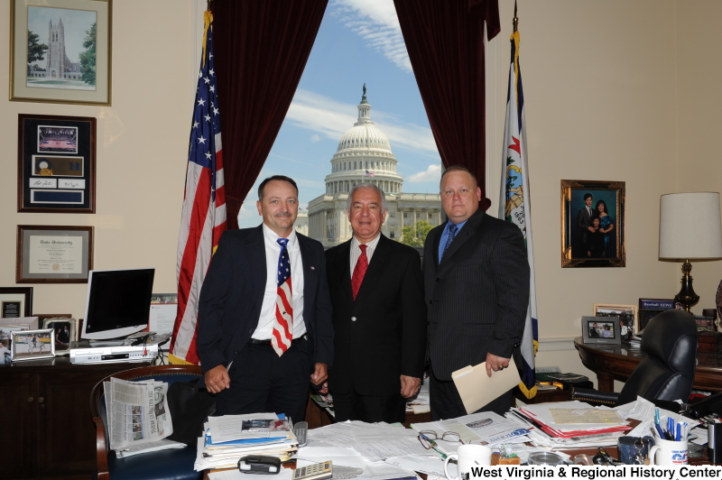 Congressman Rahall stands in his Washington office with two men, one of whom wears a United States flag-patterned tie.